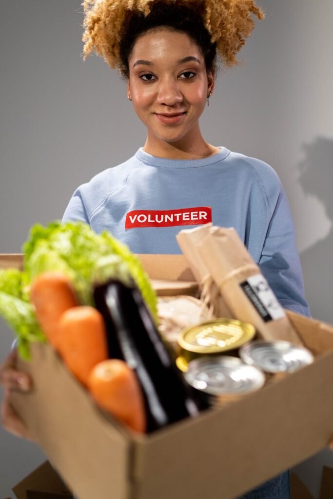 Volunteer holding a box of free fresh vegetables and canned goods at a San Antonio food pantry